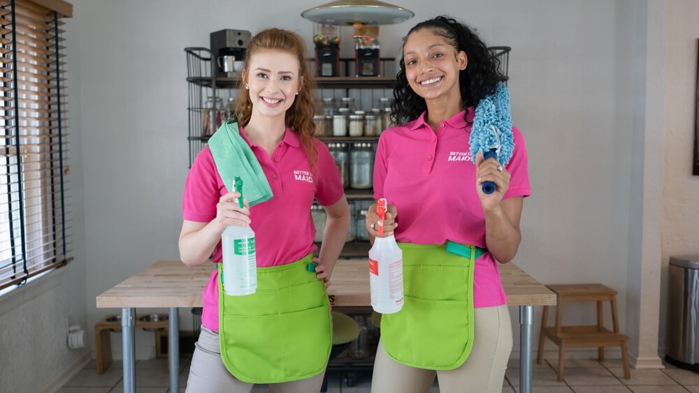 Two professional cleaners smiling with their cleaning products.
